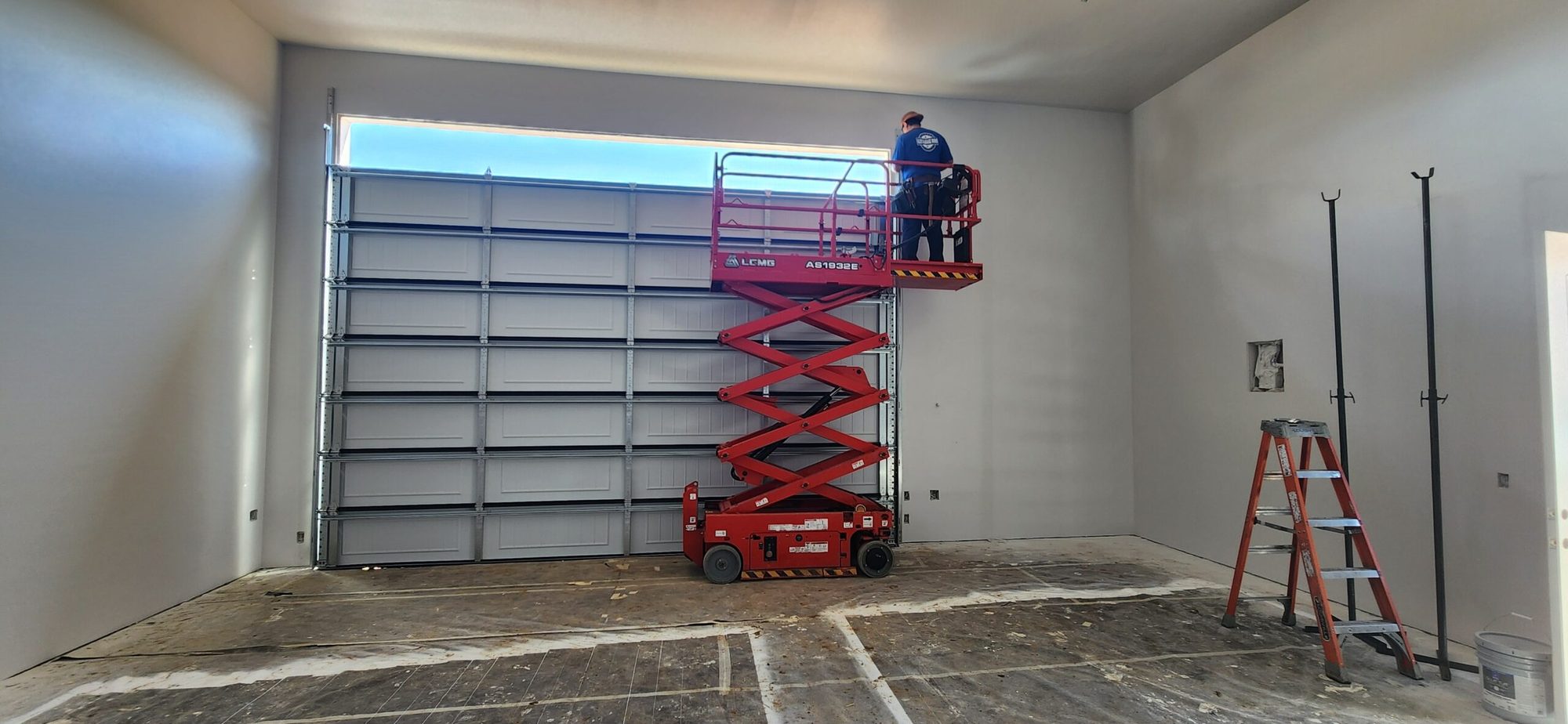 Commercial sectional garage door with a red scissor lift during installation