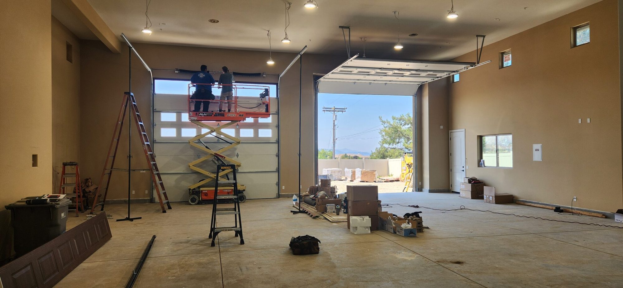 Glen's technicians on a lift installing a large new garage door inside a home